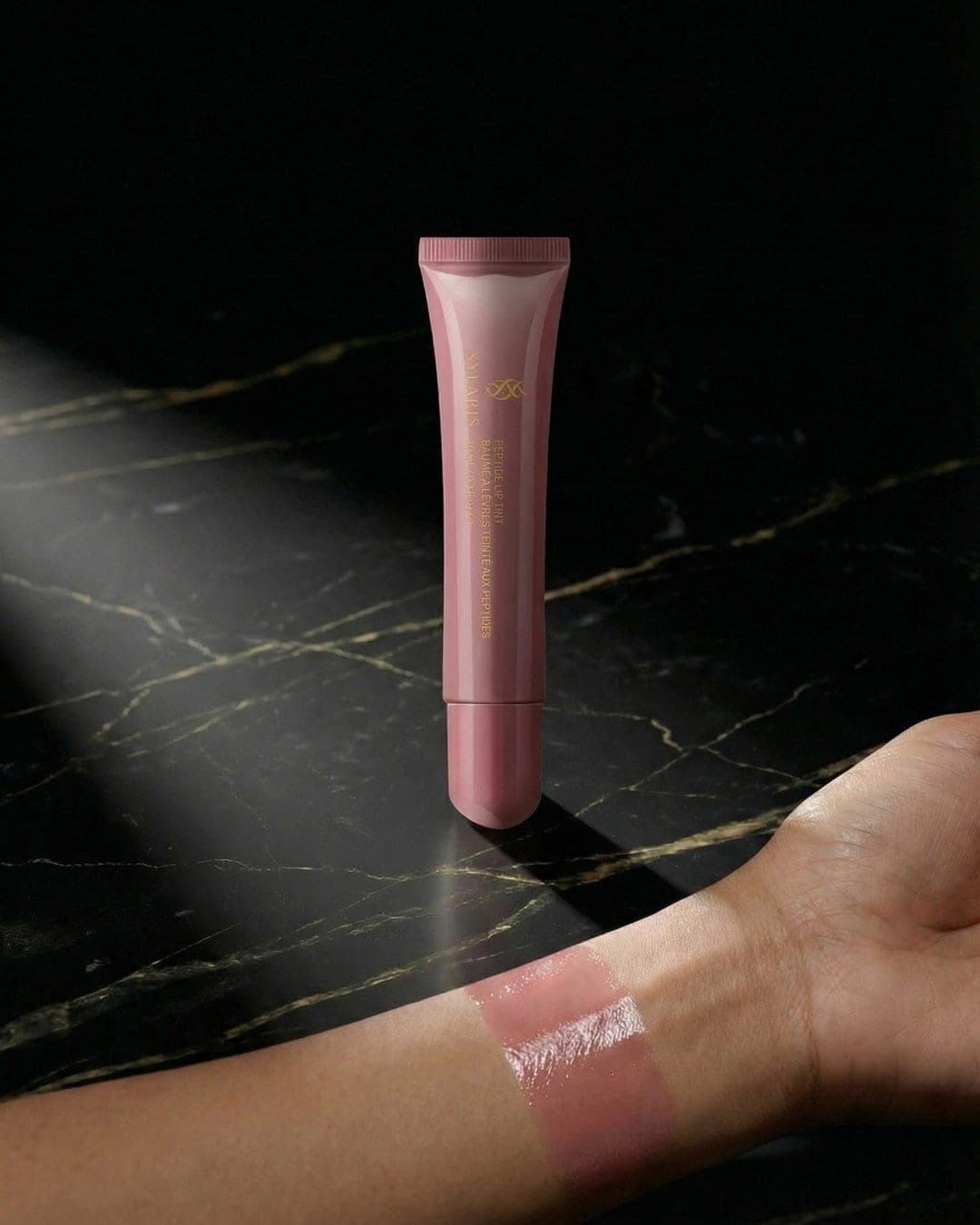 Pink Sylaris lip tint swatch on a wrist over black marble, AI-generated ad still